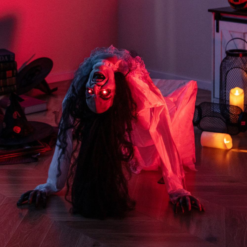 Crawling woman ghost decoration with LED eyes, sound effects, and polyester fabric for spooky Halloween ambiance.