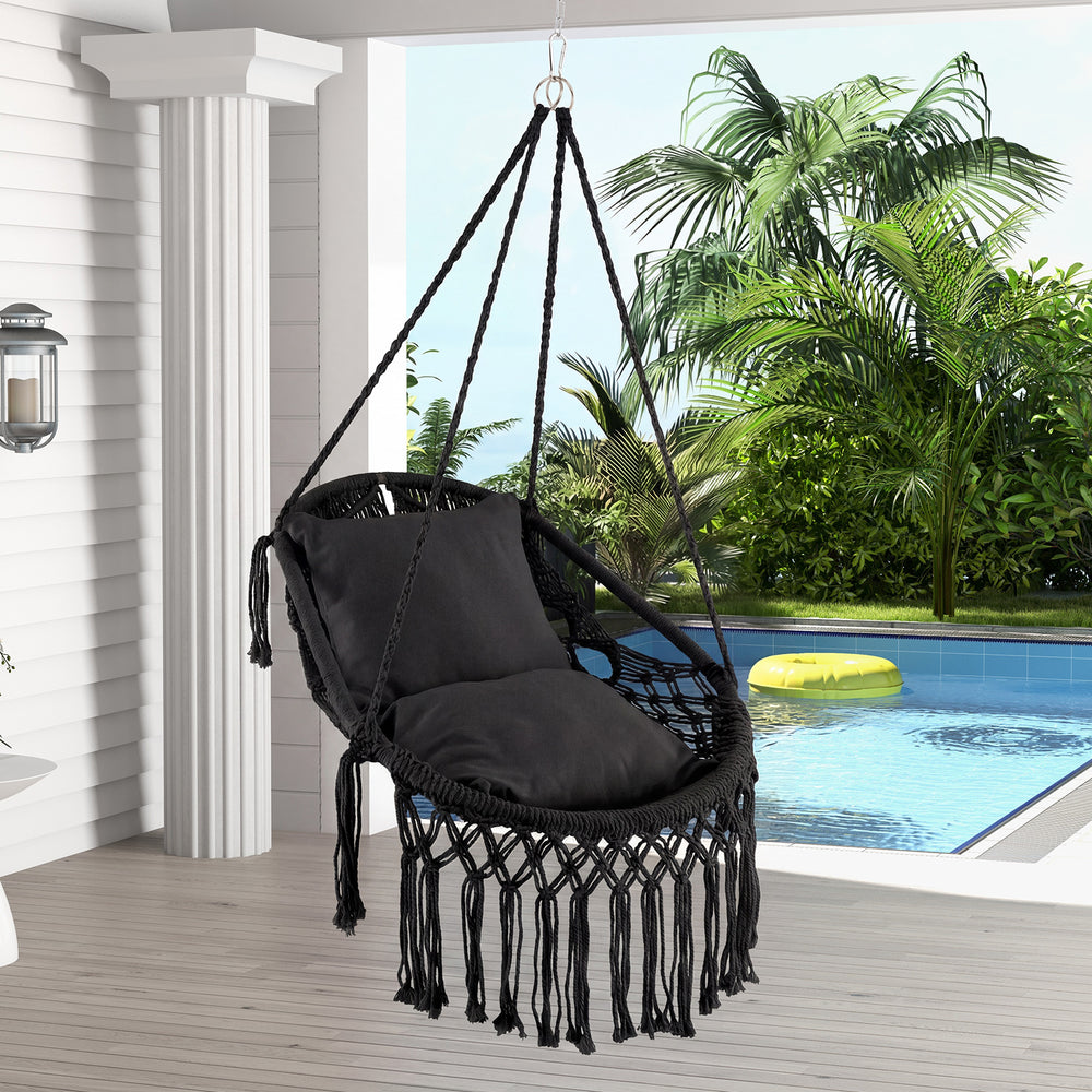 Hanging hammock chair in black with soft cushions and tassels, perfect for indoor or outdoor relaxation by the pool.