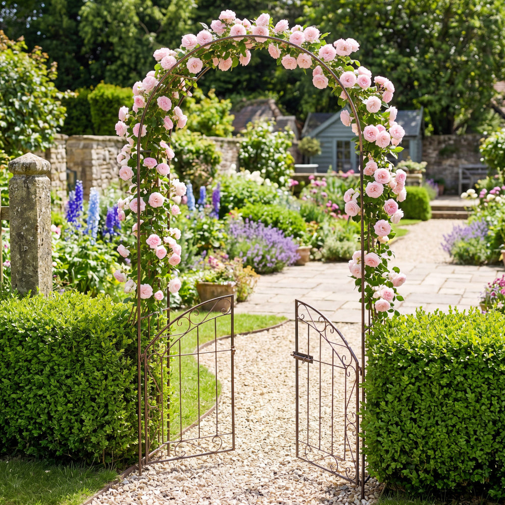 Heavy-duty bronze metal garden arch with gate, featuring floral trellis for climbing plants, ideal for outdoor events.