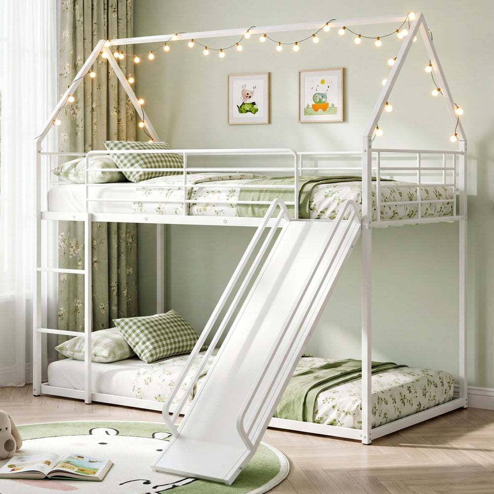 House-shaped metal twin over twin low bunk bed in white with slide and decorative lights for children's rooms.