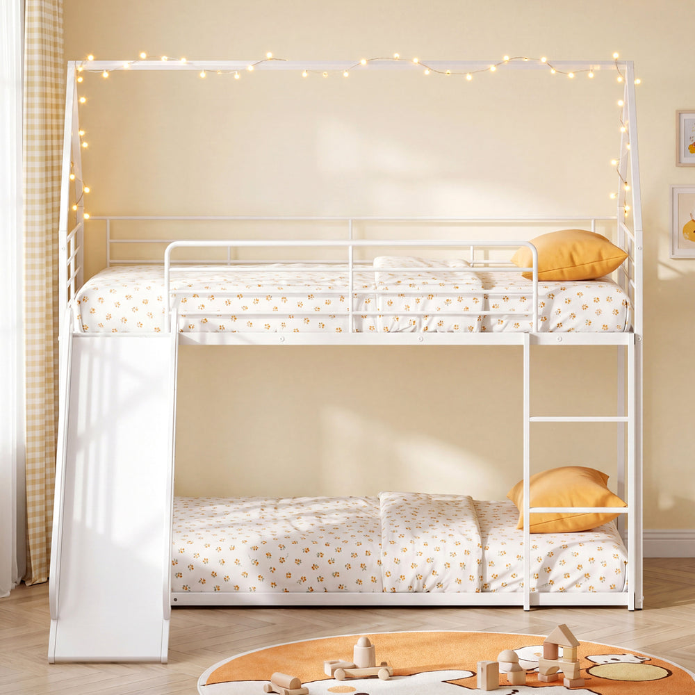 House-shaped metal twin over twin low bunk bed in white with cozy bedding and decorative fairy lights for children's.