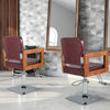 Hydraulic barber chair with red PVC leather, wooden armrests, and 360-degree swivel for hairstylist convenience.