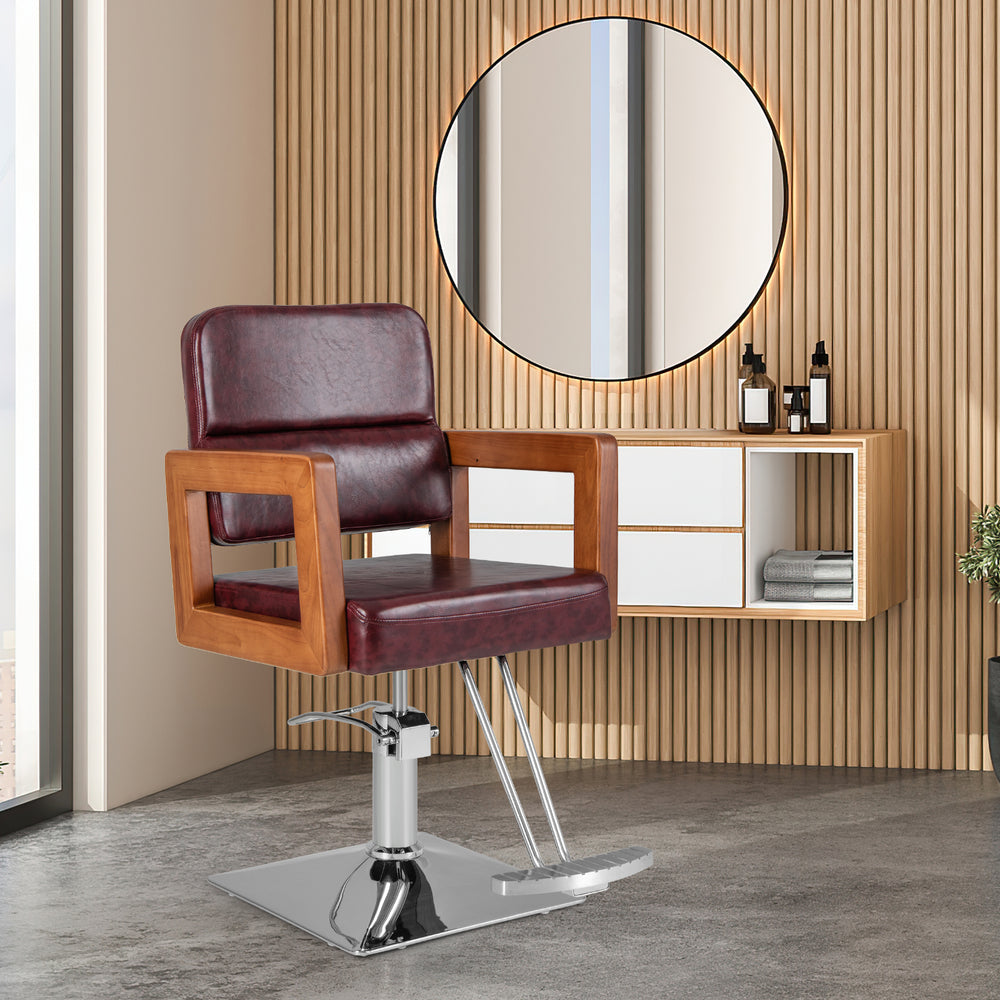 Hydraulic barber chair with red PVC leather, wooden armrests, and 360-degree swivel for hair styling convenience.