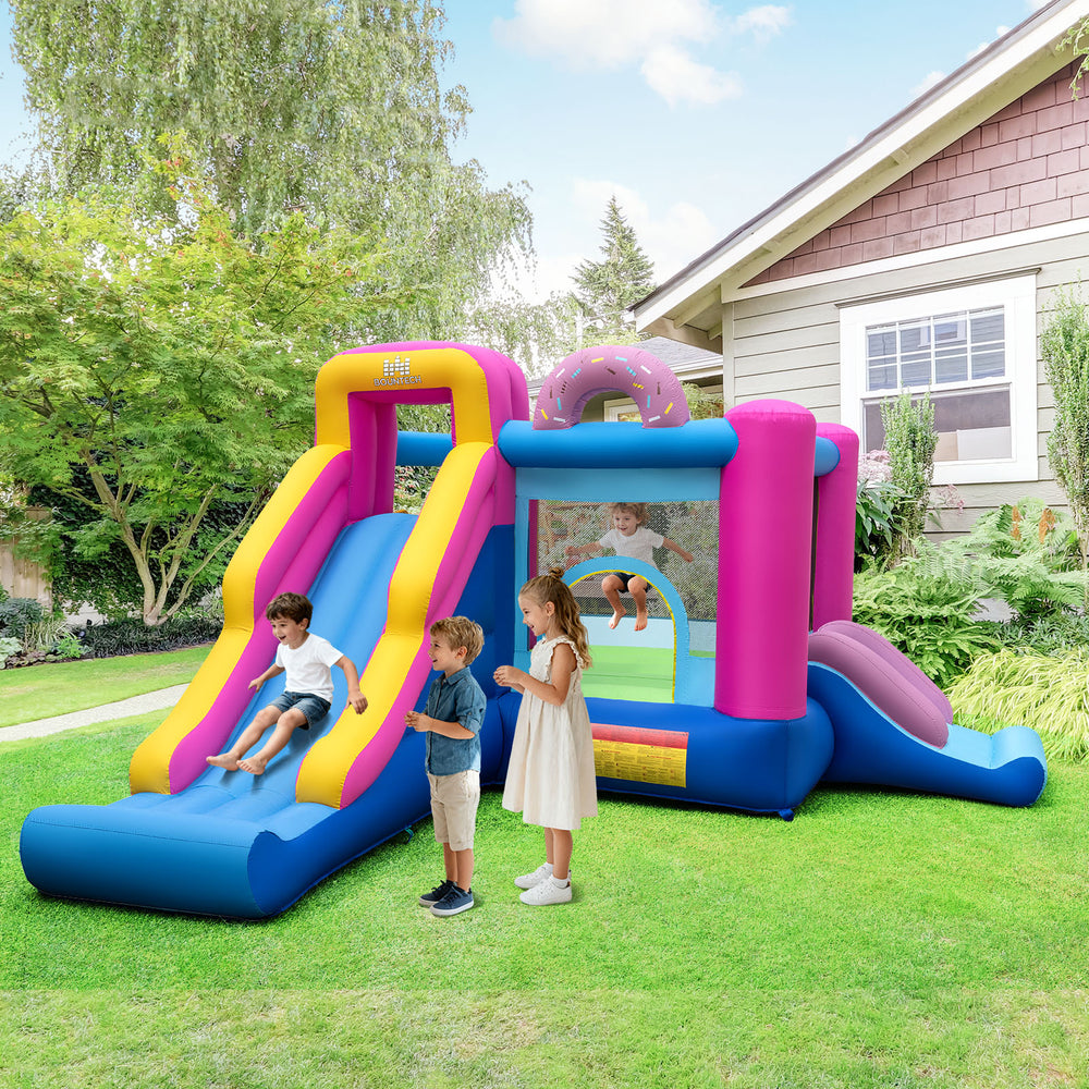 Inflatable bounce house with slides and basketball hoop, featuring a doughnut theme for backyard fun and safety.