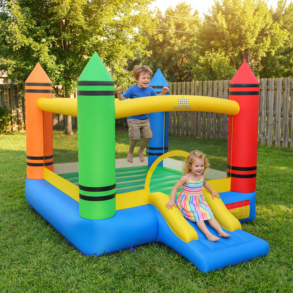 Kids jumping in the colorful inflatable bounce house with crayon theme and slide, perfect for outdoor play and fun.