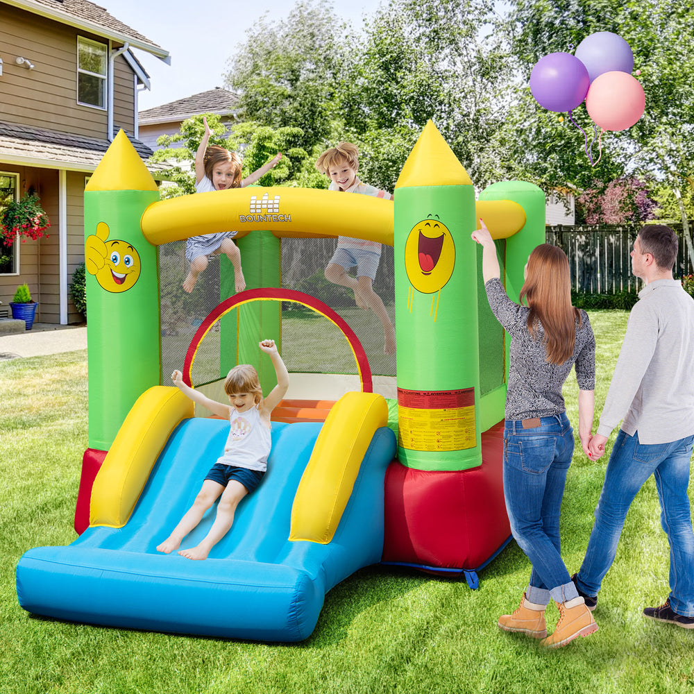 Smiley face inflatable bounce house with slide and basketball hoop, perfect for outdoor fun and playtime for kids.