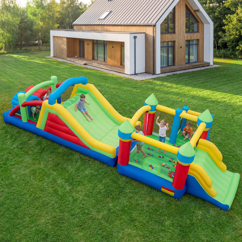 Inflatable obstacle course bounce house with dual slides, climbing wall, and tunnels for outdoor fun and play.