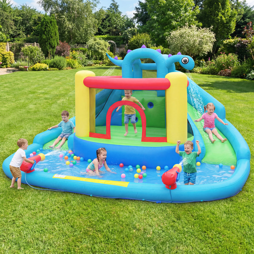 Dinosaur-themed inflatable water slide park with double slides, splash pool, and kids playing in the backyard.