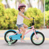 Kids bike in pink with training wheels, showcasing a child riding confidently with a stylish helmet for added safety.