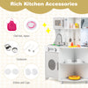 Kids kitchen accessories including chef hat, apron, cookware, and dishes for imaginative play in a gray wooden kitchen.