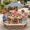 Kids enjoying snacks at a natural wood hexagonal picnic table with an adjustable striped umbrella in a garden setting.