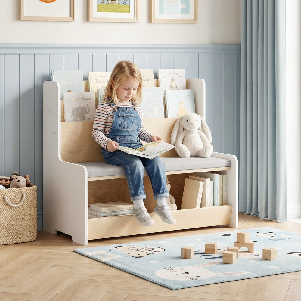 Kids reading nook featuring a white bench bookshelf with cubbies, soft cushion, and rounded corners for safety.