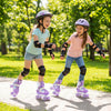 Two girls roller skating in a park wearing purple kids roller skates with light-up wheels and safety gear.