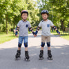 Two children roller skating hand in hand, wearing adjustable black roller skates with light-up wheels in a park.