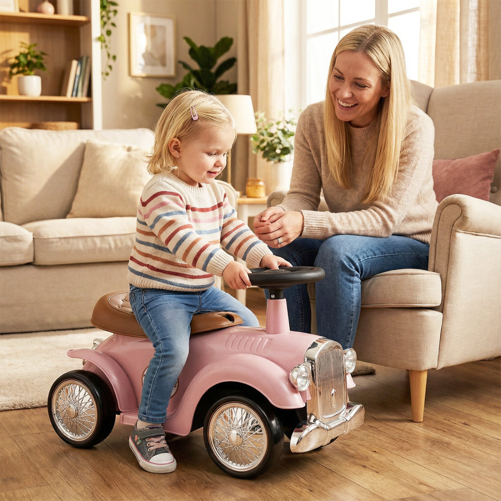 Kids sit-to-stand vehicle in pink with working steering wheel and under-seat storage, perfect for indoor playtime.