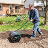 Lawn roller with U-shape handle, filled with water, used for leveling soil in a garden. Ideal for landscaping projects.