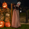 Life-size Halloween animatronic old lady hag prop standing by jack-o'-lanterns, featuring glowing red eyes and a creepy.