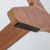 Close-up of the walnut wood base of a lockable jewelry armoire with non-slip foot pads for stability and floor.