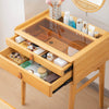 Bamboo makeup vanity table with two drawers, tempered glass top, and rotating mirror for organized cosmetics storage.