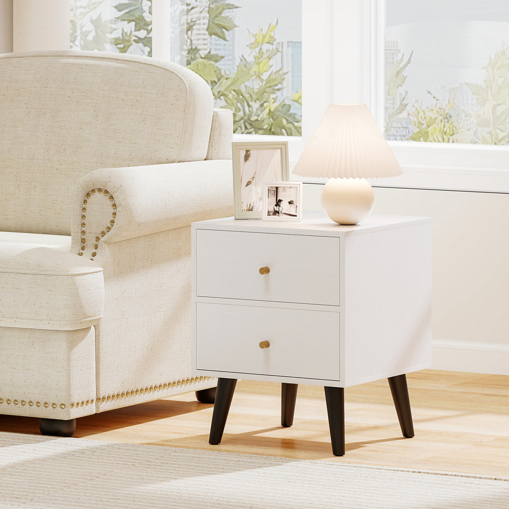 Mid Century Modern bedside table in white with golden knobs, featuring two drawers and raised support legs for easy.