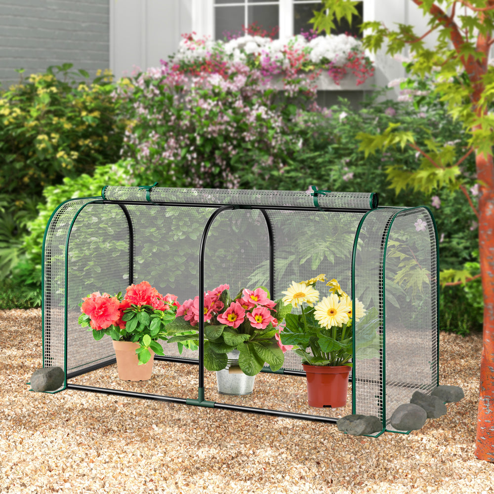 Mini tunnel greenhouse showcasing a roll-up zipper door, secured with U-shaped stakes, ideal for cultivating seedlings.