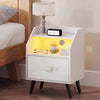 Nightstand in white featuring LED lights, a fabric drawer, open storage shelf, and built-in power outlets for convenience.