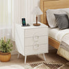 Modern white nightstand with three drawers, power outlets, and cable hole for organized charging beside the bed.