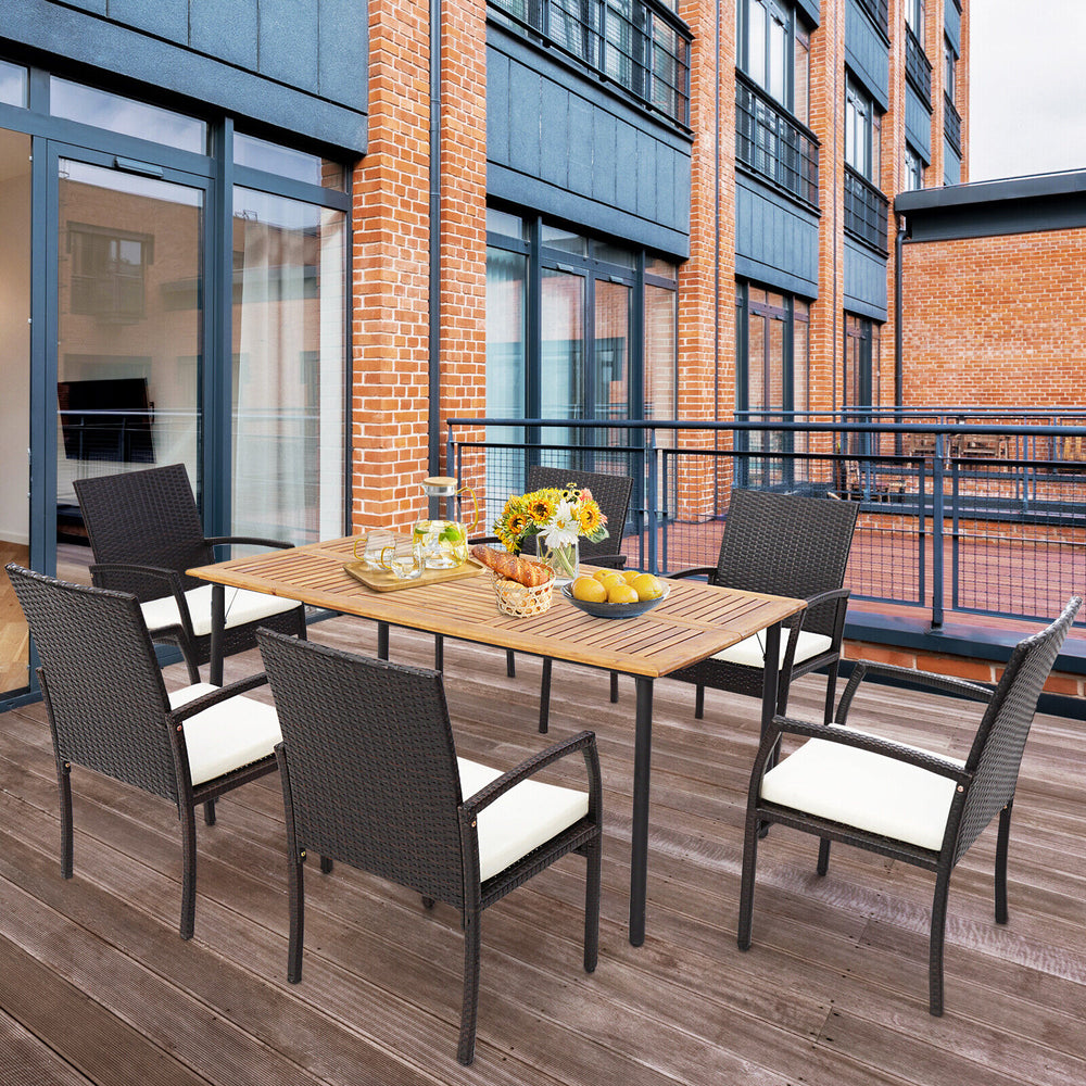 Patio wicker dining set featuring four armchairs with soft zippered cushions, perfect for outdoor dining on a balcony.