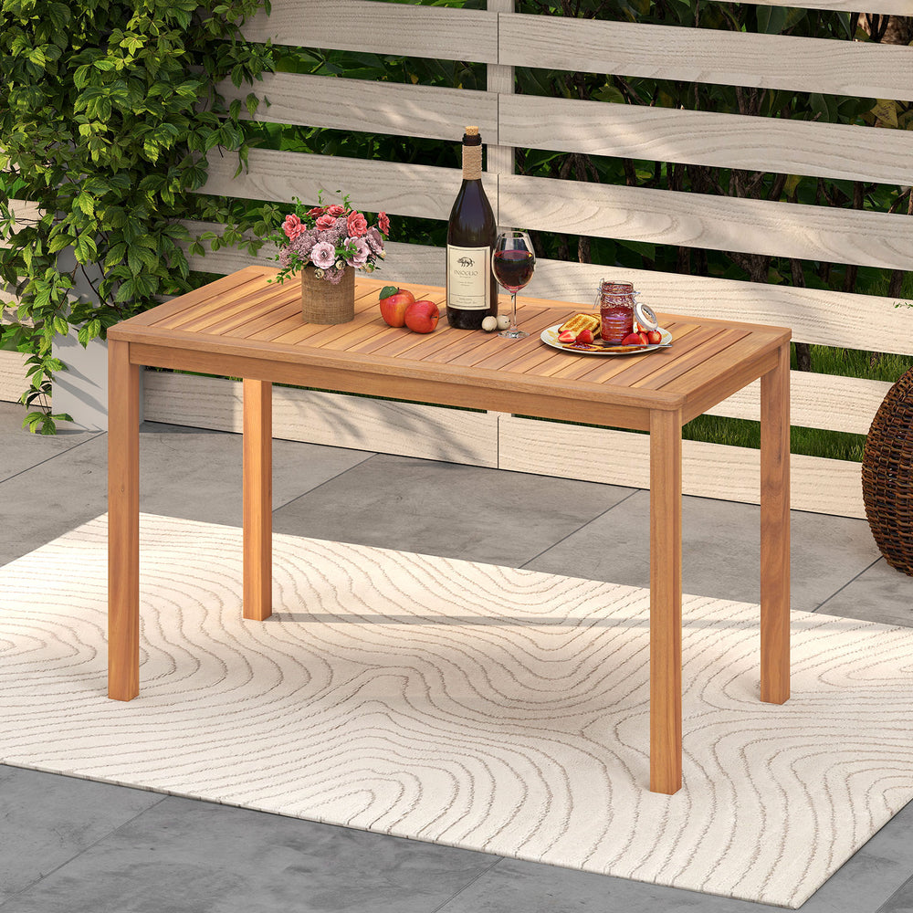 Acacia wood dining table with a slatted top, featuring rounded corners, ideal for outdoor dining on a balcony or deck.