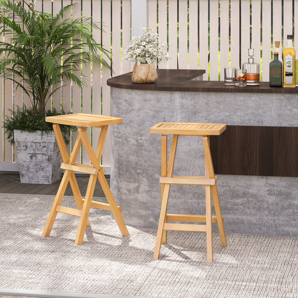 Set of 2 folding outdoor bar stools in teak wood with ergonomic saddle seats, perfect for patio or backyard use.