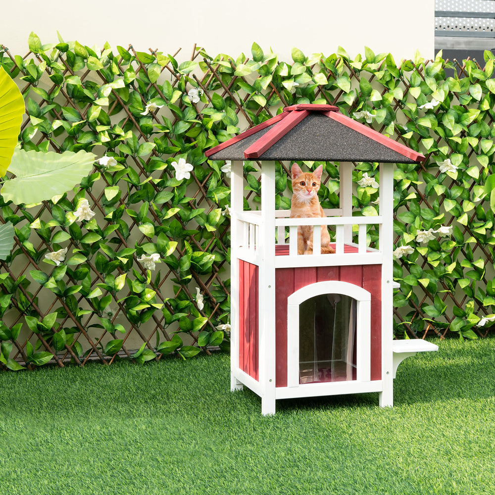 2-story wooden cat house in red and white with asphalt roof, balcony, and guardrails for outdoor pet relaxation.