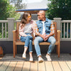 Two people sitting on a 2-person outdoor garden bench made of durable teak wood, perfect for patios and yards.
