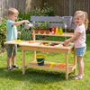 Children playing with the Outdoor Mud Kitchen, featuring a wooden playset with sink, faucet, and storage shelves.