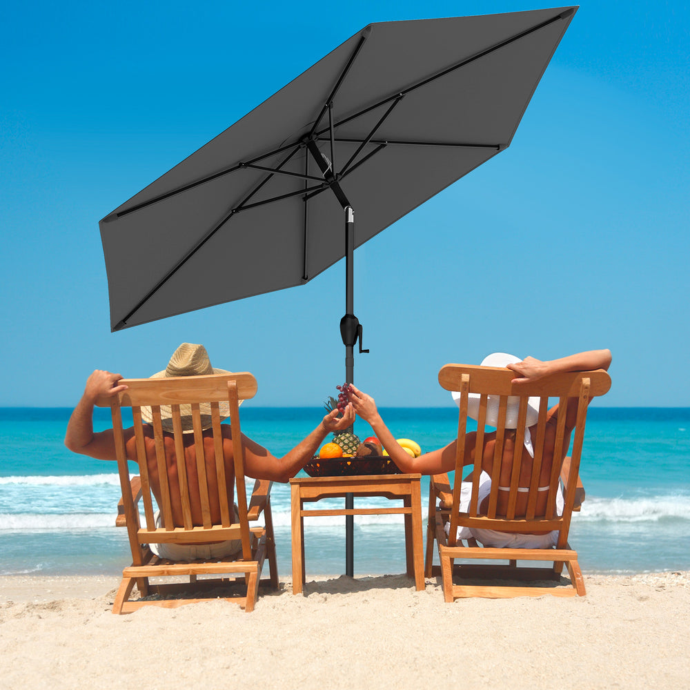 Gray 7.5 feet outdoor patio market umbrella with push button tilt, providing shade for beach relaxation.