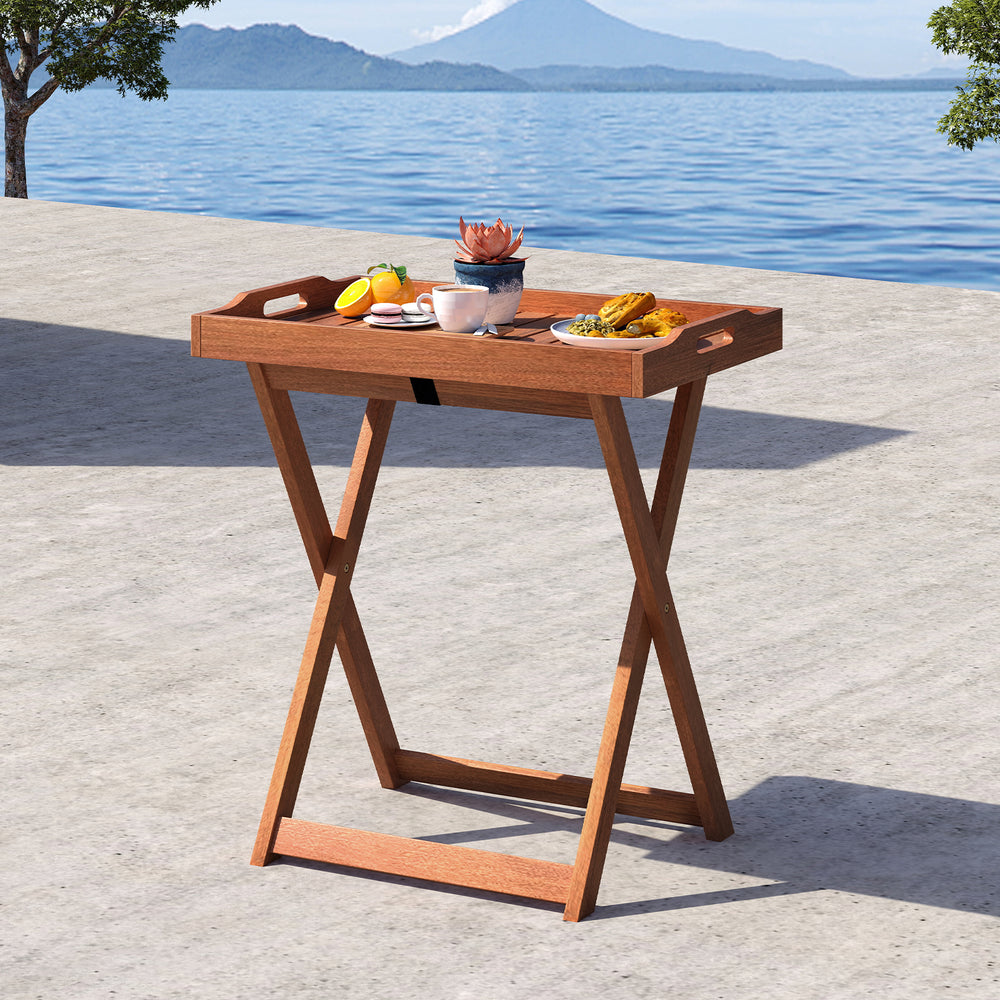 Foldable outdoor patio tray table in solid wood with removable top, ideal for poolside or balcony use.