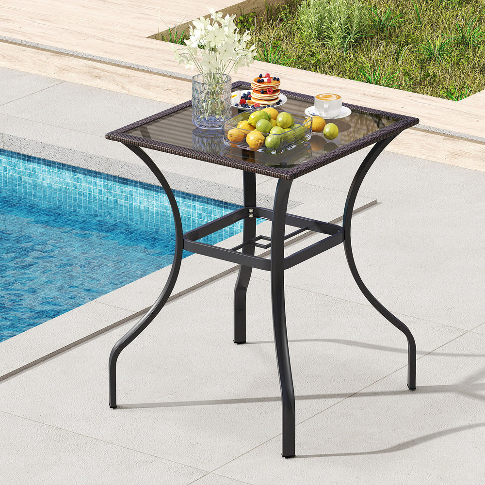 Square outdoor patio table with rattan edging and glass top, perfect for indoor or outdoor use by the pool.