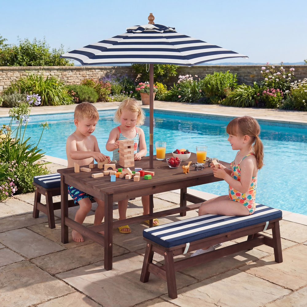 Kids enjoying playtime at the outdoor wooden picnic table with removable umbrella and blue cushions by the pool.