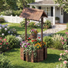 Outdoor wooden wishing well planter with rustic burnt-like finish, featuring a bucket for smaller plants in a garden.