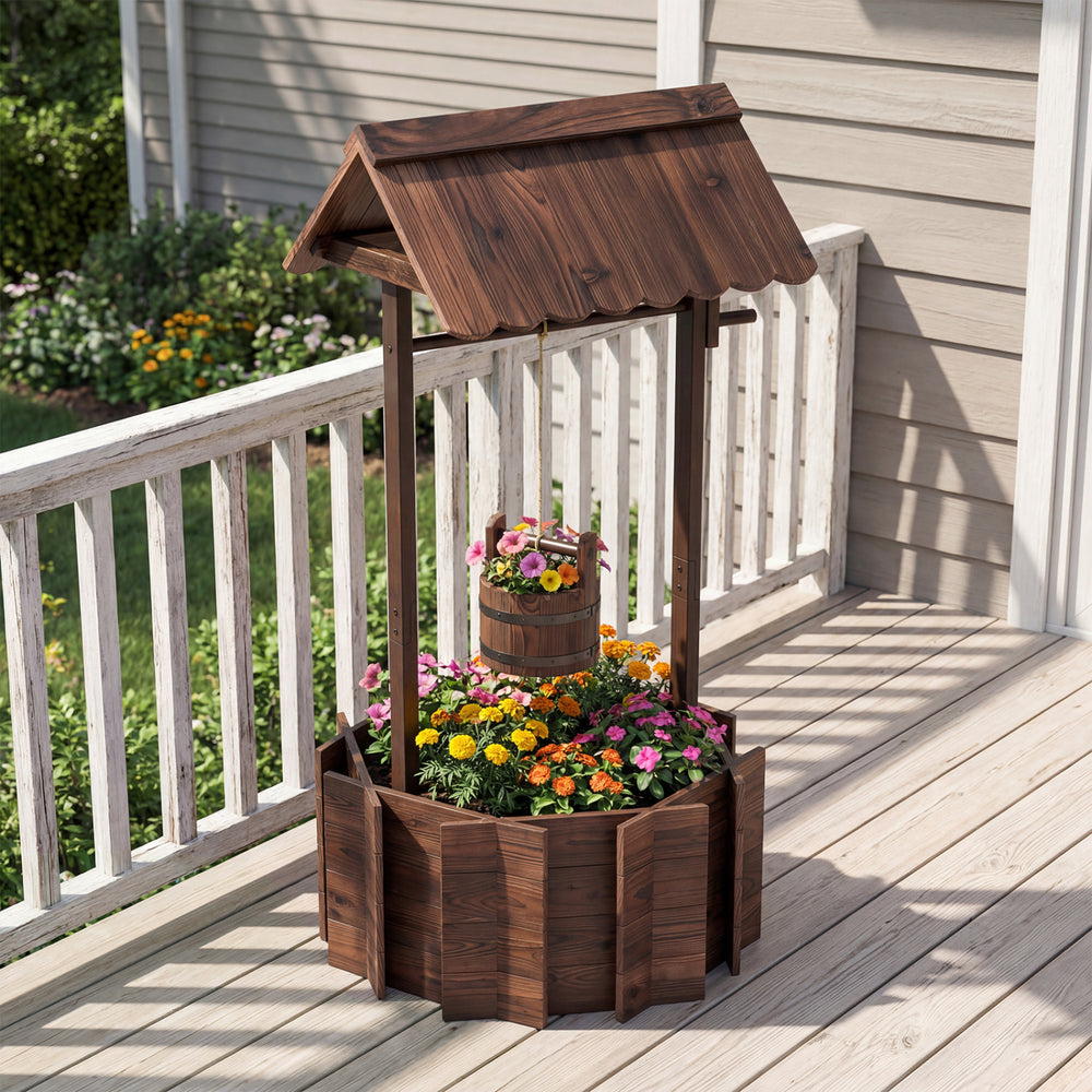 Outdoor wooden wishing well planter with burnt-like finish, featuring a bucket for smaller plants, perfect for gardens.