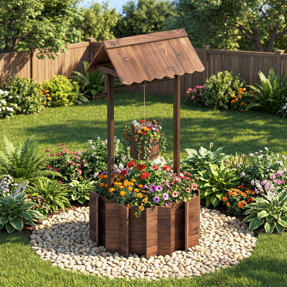 Outdoor wooden wishing well planter with burnt-like finish, featuring a hanging bucket for flowers in a garden setting.