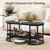 Oval black coffee table with 2-tier storage shelf and 5-inch clearance for easy robotic cleaning in a cozy living room.