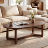 Oval coffee table with a thickened walnut top and V-shaped wood base, perfect for snacks and books in a cozy living.