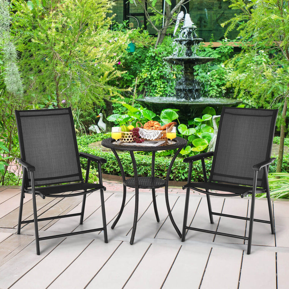 Set of 2 black outdoor patio folding chairs with ergonomic armrests, placed on a deck in a lush garden setting.