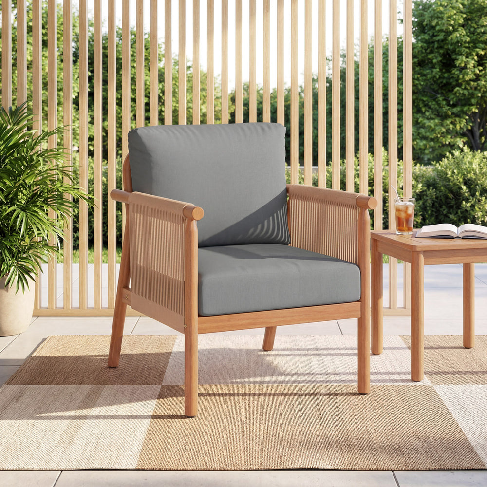 Acacia wood patio chair with gray cushions and woven rope armrests, perfect for backyard relaxation.