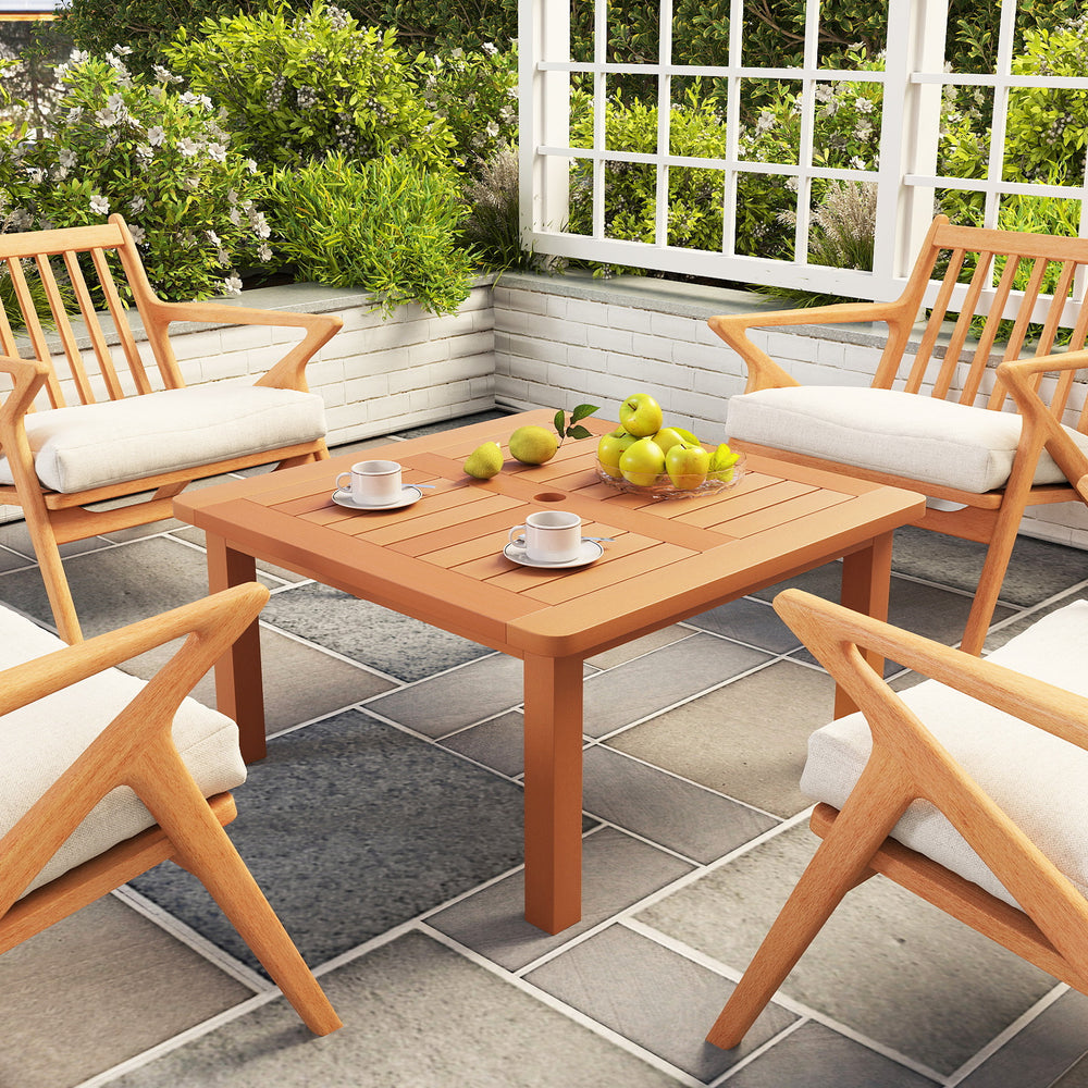 Solid wood patio coffee table with teak oil finish, featuring a slatted top and built-in umbrella hole for outdoor use.
