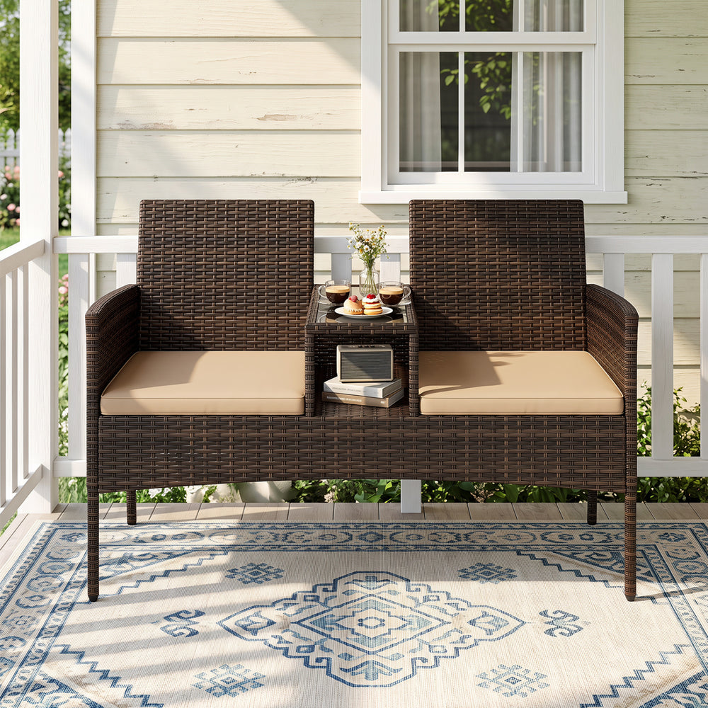 Curved brown patio loveseat made of handwoven PE rattan with built-in coffee table and high-density cushions for comfort.