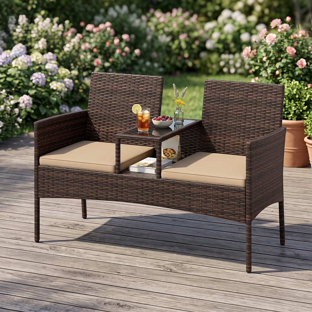 Patio loveseat set in brown wicker features ergonomic curved back, high-density cushions, and built-in coffee table for outdoor relaxation.