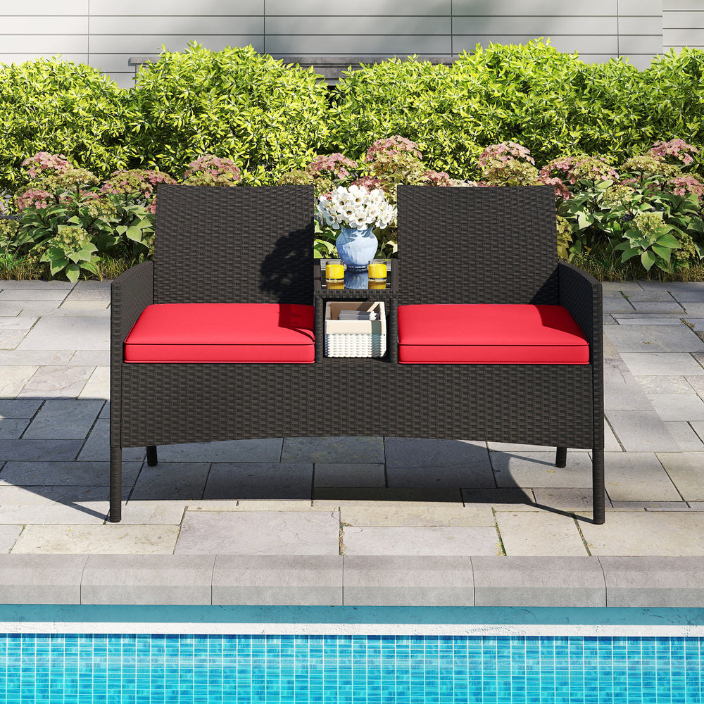 Patio loveseat with built-in table, red cushions, and hand-woven PE rattan, perfect for poolside relaxation.
