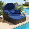 Patio PE rattan daybed with retractable canopy and navy cushions, perfect for lounging by the poolside or garden.