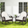 Patio rattan rocking chairs with white cushions, featuring ergonomic design, suitable for outdoor relaxation.